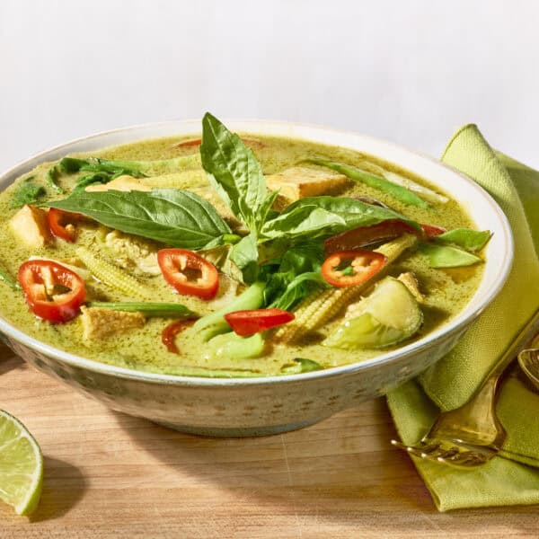 A bowl of Thai green curry topped with fresh herbs.