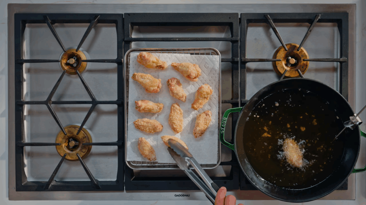 Fried chicken wings draining on paper towels.