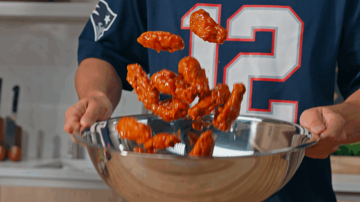 Nick DiGiovanni tossing fried chicken wings with buffalo sauce. 