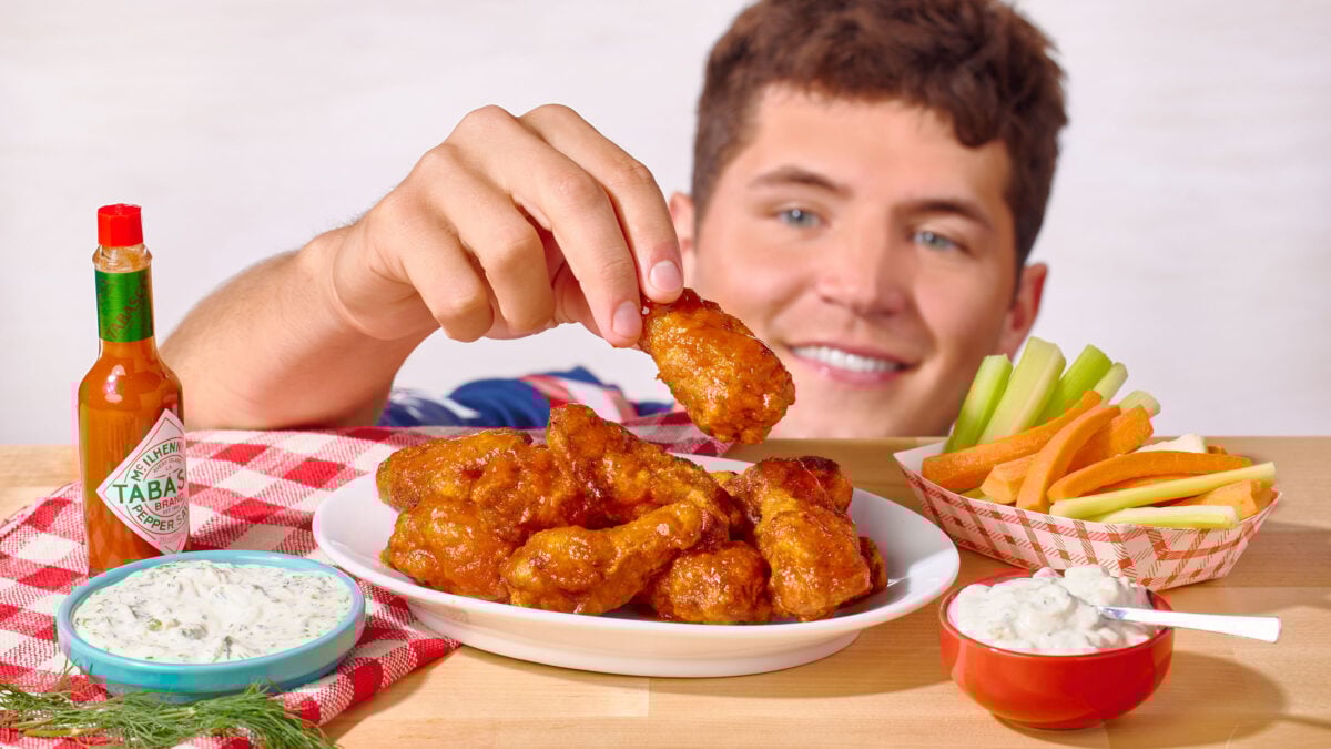 Nick DiGiovanni lifting a buffalo chicken wing from a platter. 