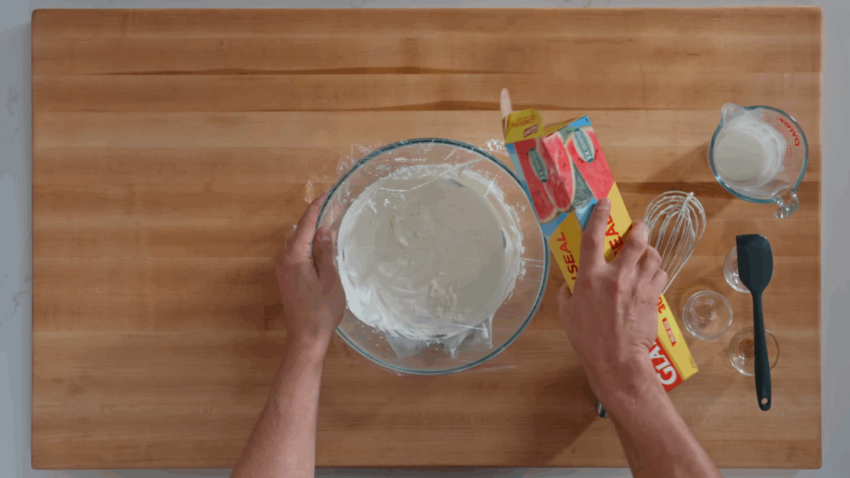 Nick DiGiovanni covering a bowl of whipped cream with plastic wrap.