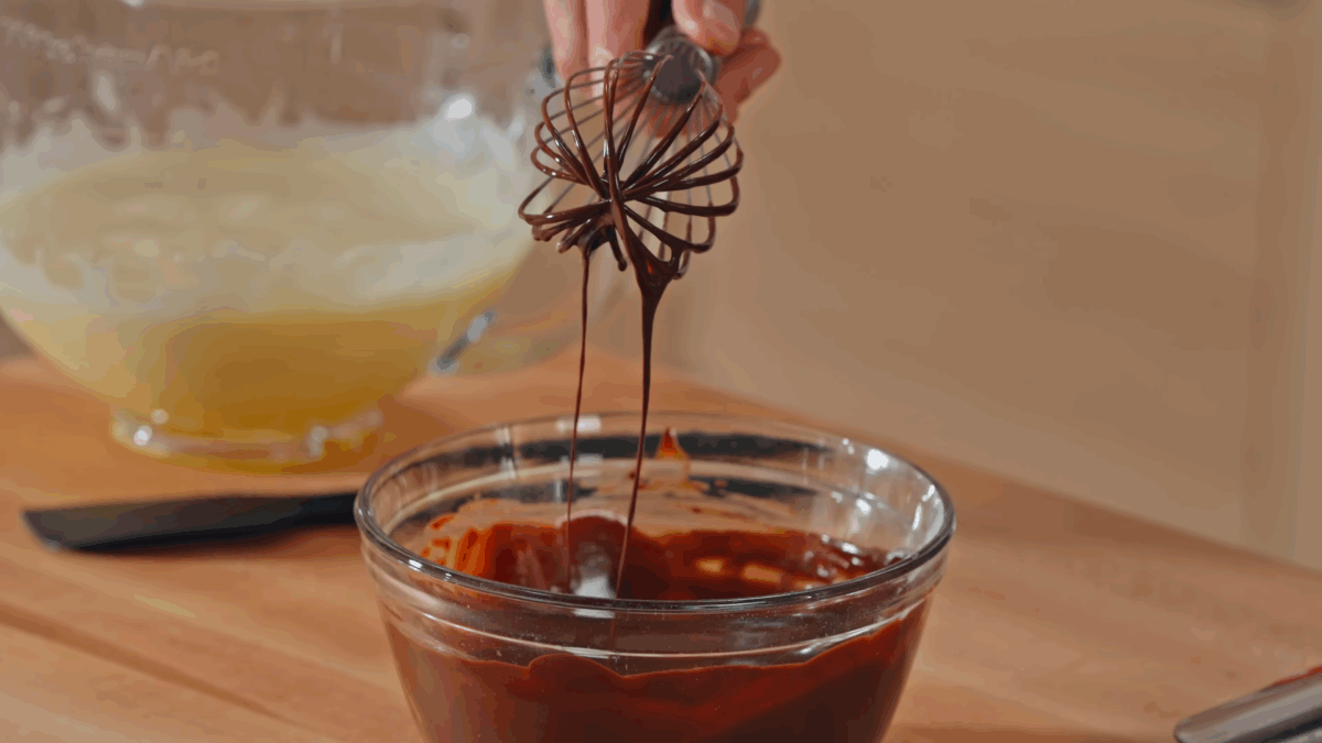 Flour being whisked into a bowl of chocolate ganache.