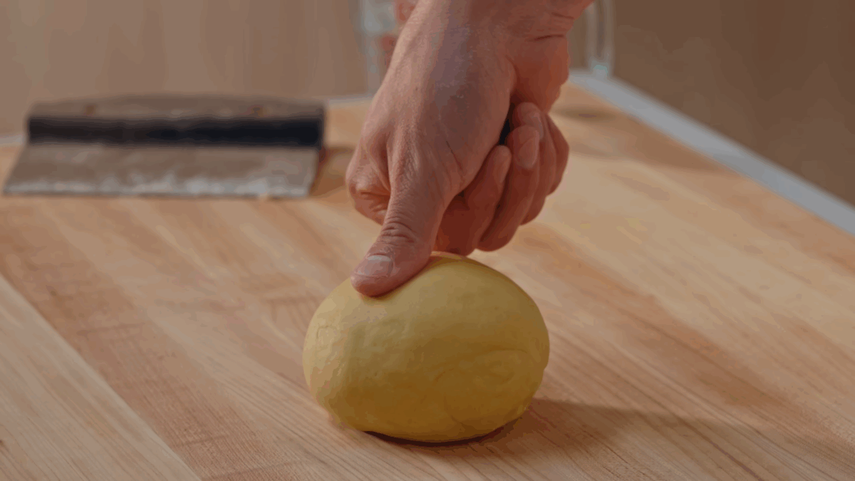 A ball of pasta dough being tested for readiness.
