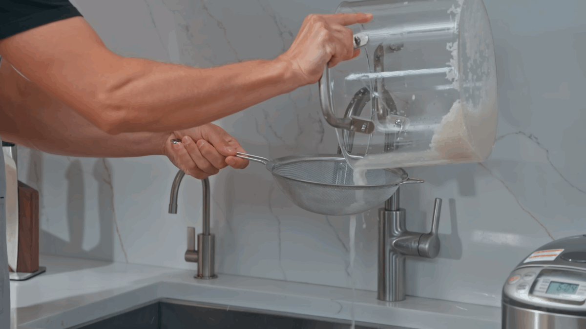 Nick DiGiovanni rinsing sushi rice in a fine mesh sieve.