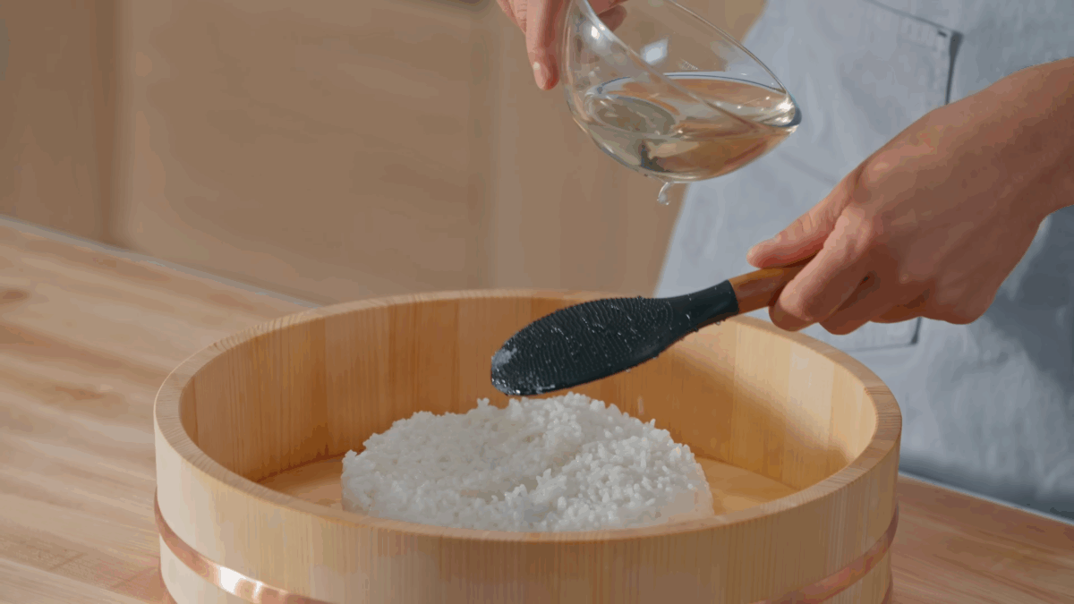 Nick DiGiovanni adding seasoned rice vinegar to sushi rice.