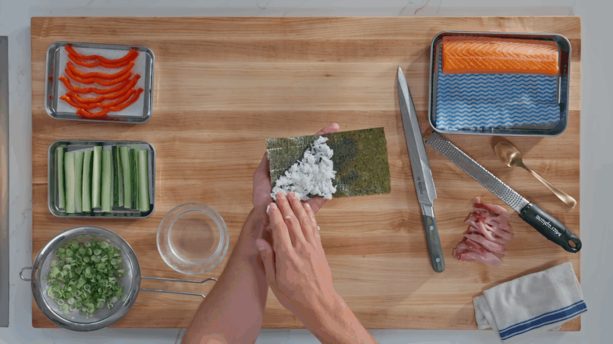 Nick DiGiovanni spreading sushi rice over a sheet of nori.