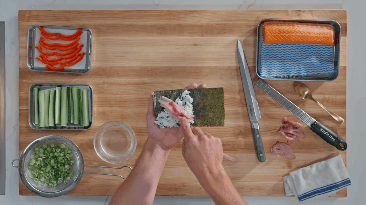 Nick DiGiovanni layering yellowtail over sushi rice on a sheet of nori.