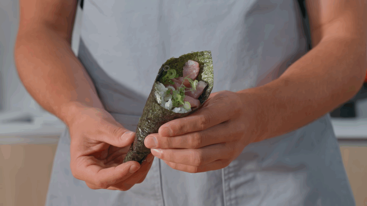Nick DiGiovanni holding a homemade hand roll made with yellowtail.