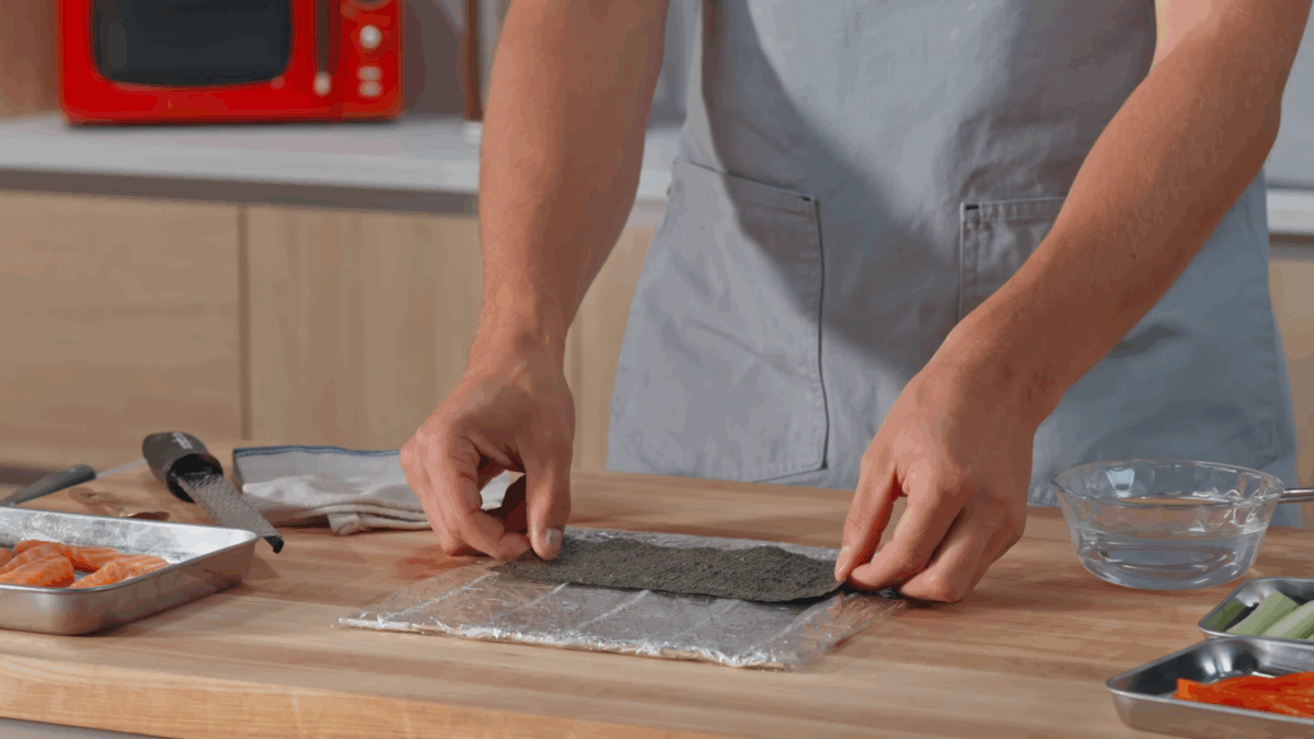 Nick DiGiovanni placing a sheet of nori on a bamboo sushi mat.
