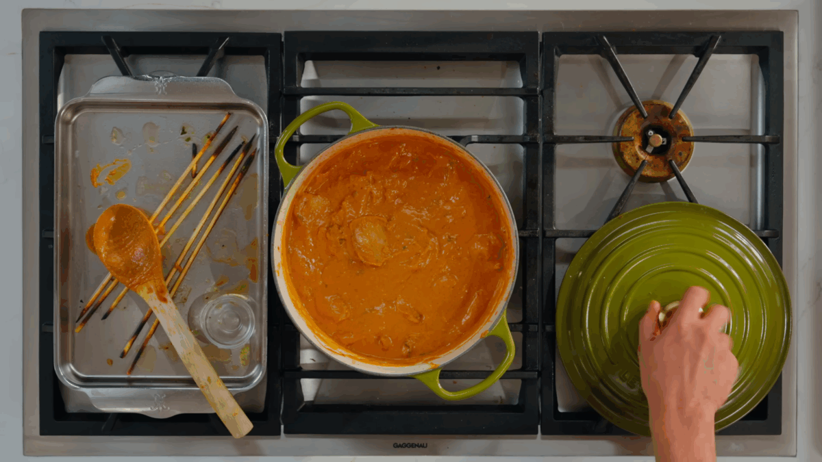 Chicken tikka masala simmering in a Dutch oven on a stovetop.