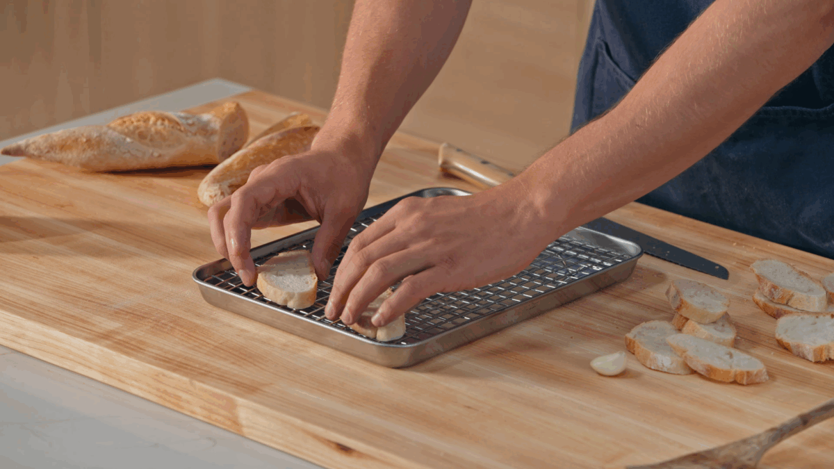 Nick DiGiovanni placing baguette pieces on a baking sheet lined with a wire rack. 