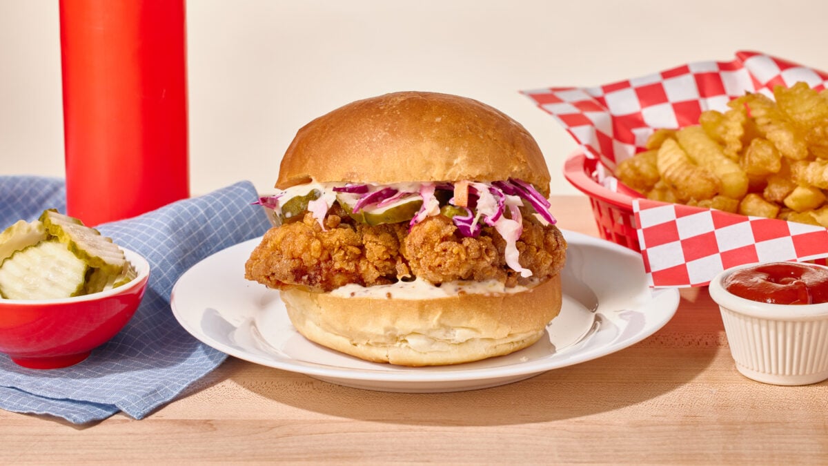 A fried chicken sandwich topped with slaw on a white plate.