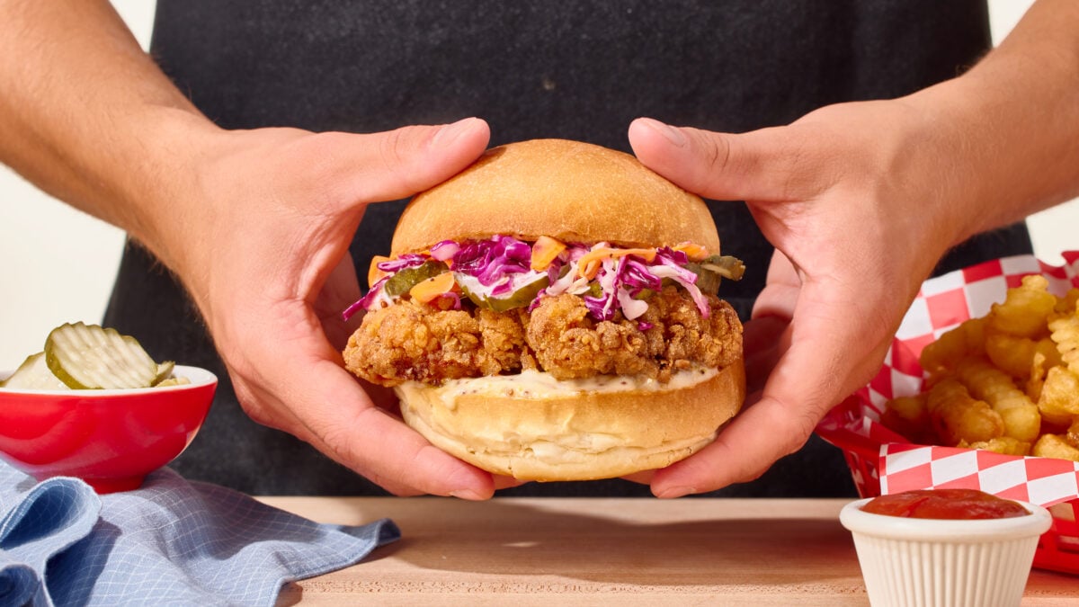 Nick DiGiovanni holding a homemade fried chicken sandwich with two hands.