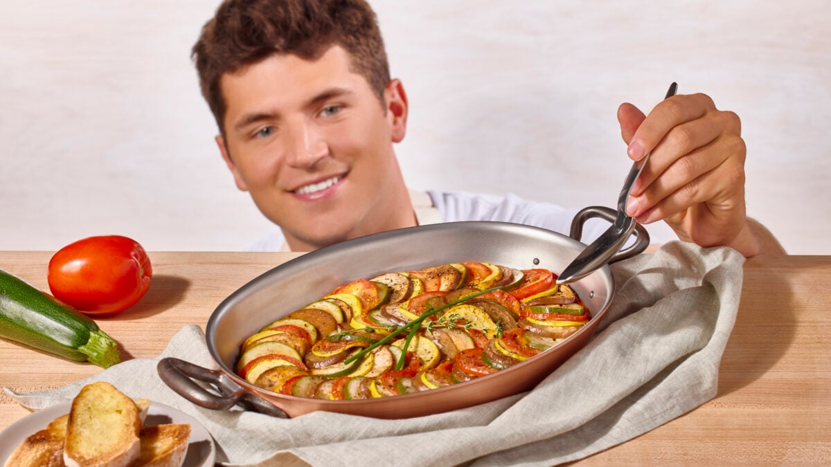 Nick DiGiovanni scooping a serving of ratatouille from a baking dish.