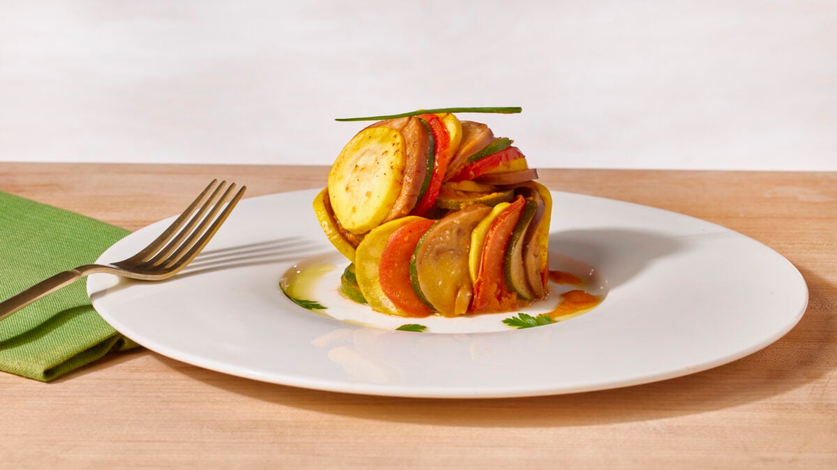 A serving of ratatouille on a plate topped with fresh herb.