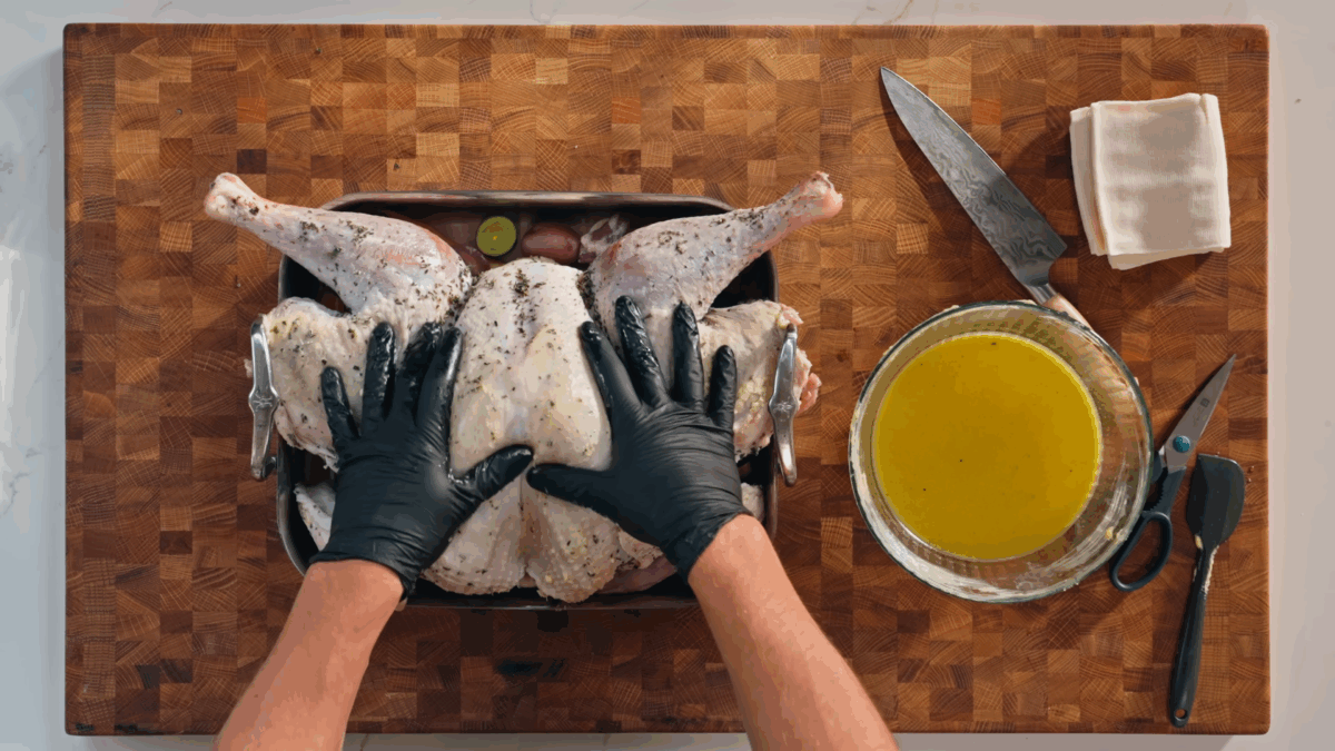 Nick DiGiovanni placing a brined turkey on top of a pan of fruits and veggies. 