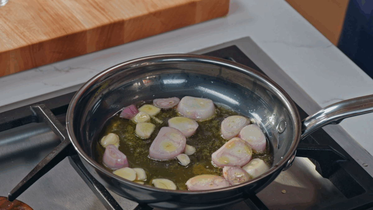Garlic and shallots cooking in oil in a skillet.