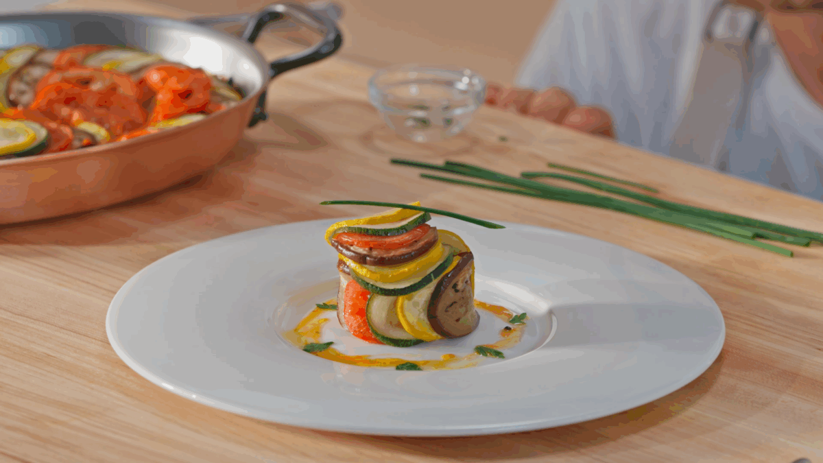 Ratatouille on a plate topped with a fresh chive.