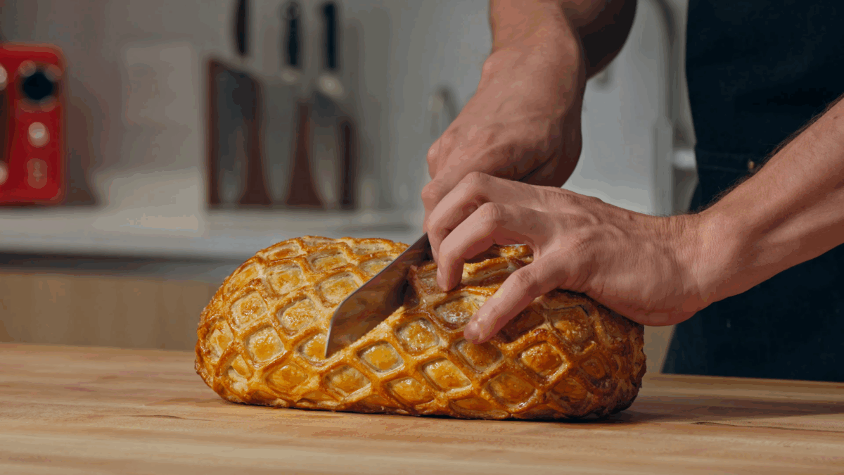 Nick DiGiovanni slicing a cooked Beef Wellington. 