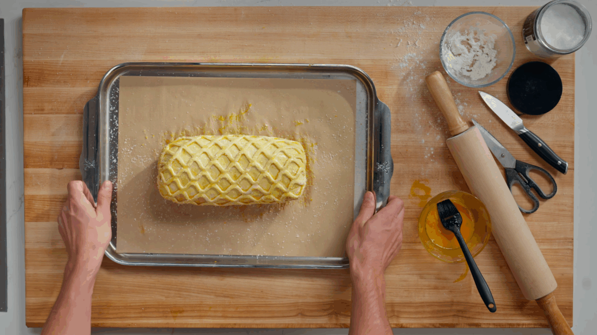 Nick DiGiovanni holding a baking sheet with an uncooked Beef Wellington. 