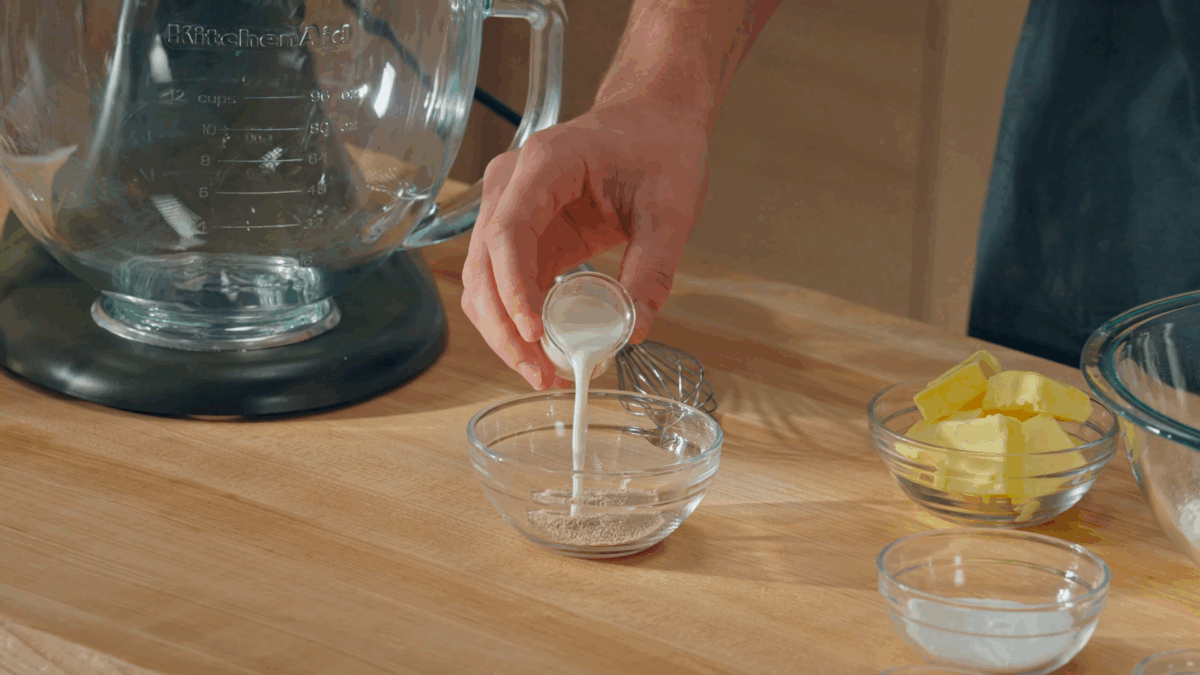Nick DiGiovanni pouring warm milk into a bowl of dry yeast. 