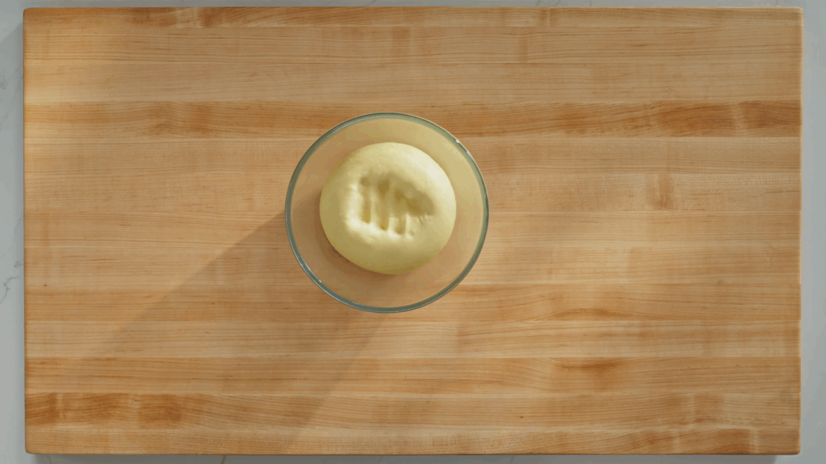 A bowl of cinnamon roll dough punched down. 