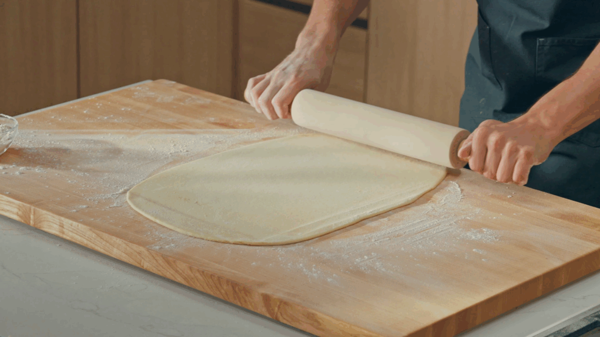 Nick DiGiovanni using a rolling pin to roll out cinnamon roll dough. 