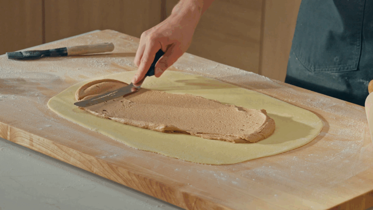 Nick DiGiovanni spreading cinnamon roll filling over cinnamon roll dough. 