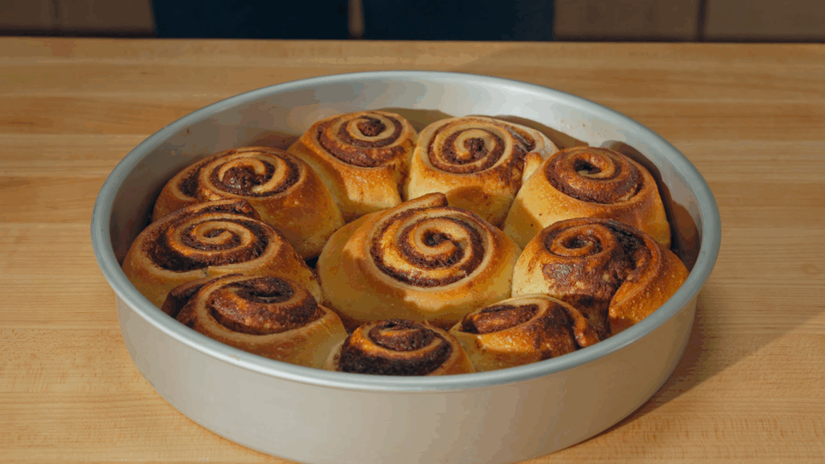 Ten baked cinnamon rolls in a round cake pan. 