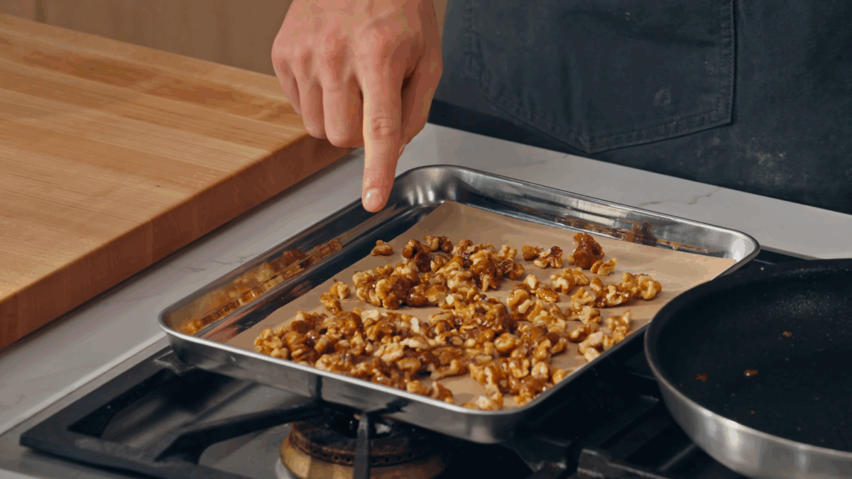 Candied walnuts on a parchment paper-lined baking sheet. 