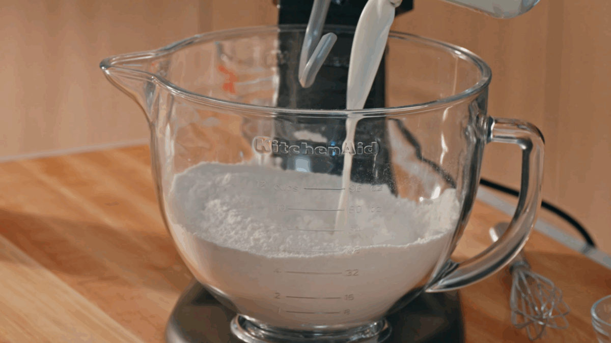 Nick DiGiovanni adding wet ingredients to croissant dough in a stand mixer. 