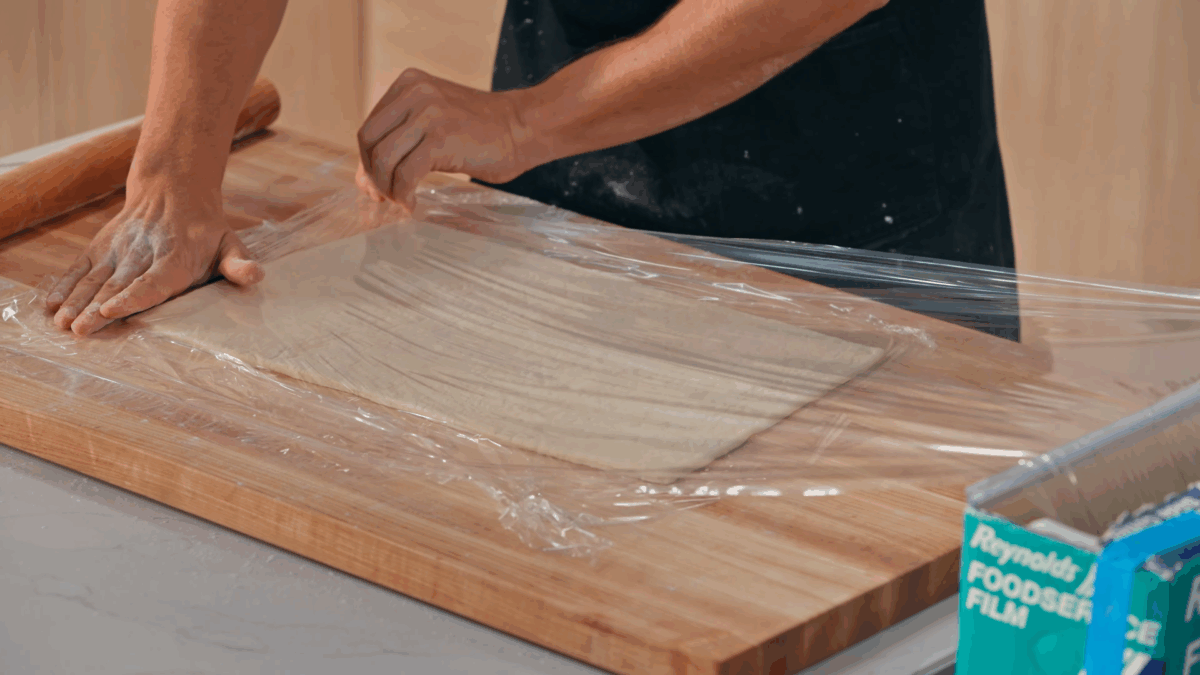Nick DiGiovanni covering croissant dough with parchment paper. 