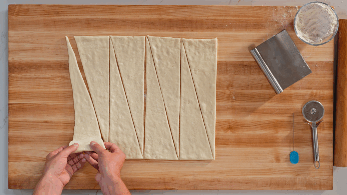 Nick DiGiovanni stretching triangles of dough for homemade croissants.