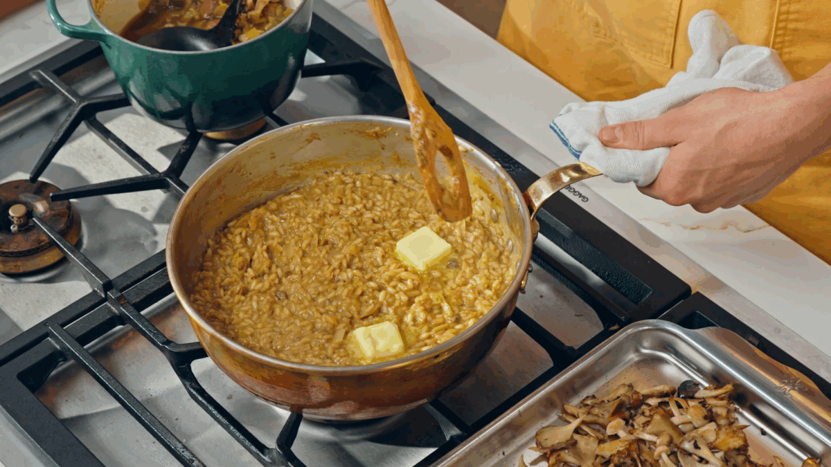 Nick DiGiovanni stirring butter into a pot of mushroom risotto.