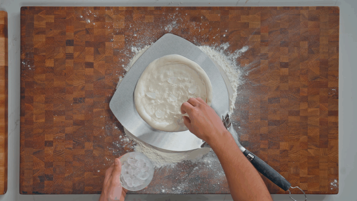 Nick DiGiovanni placing ice cubes in the center of Neapolitan pizza dough. 