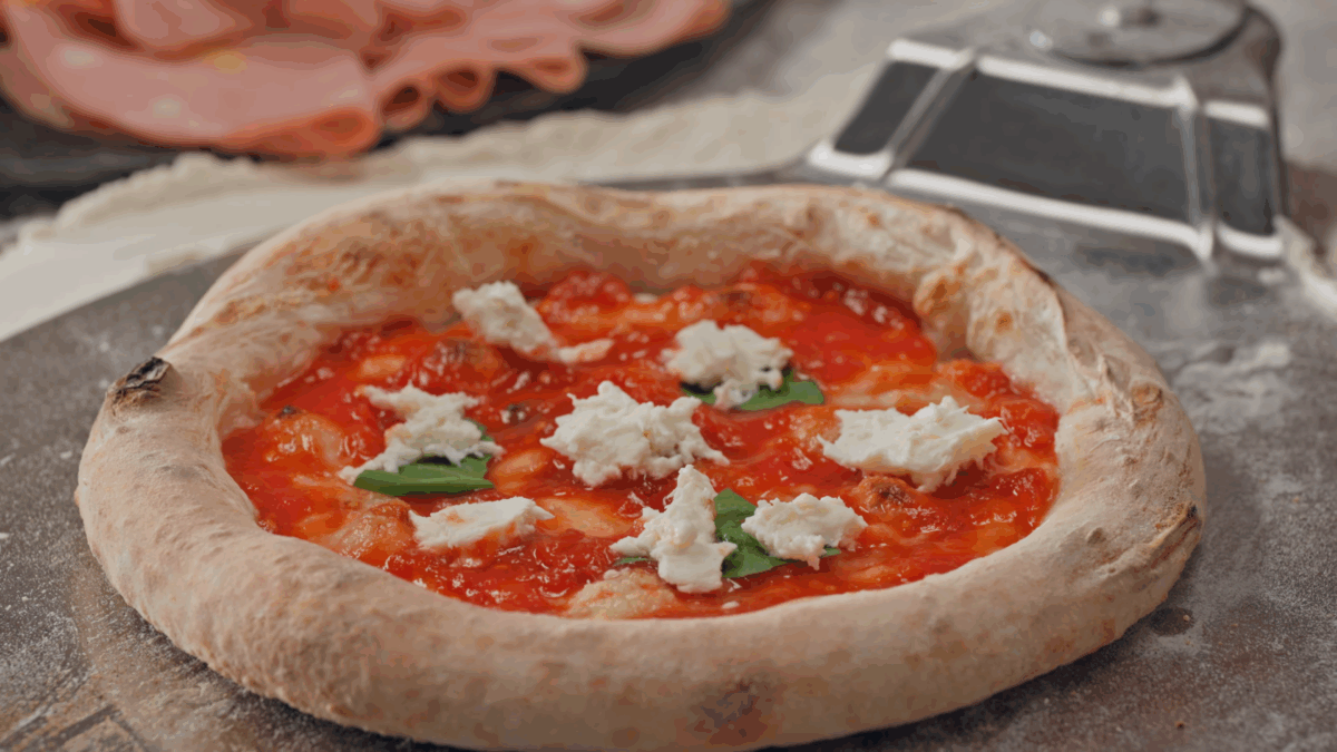 An unbaked Neapolitan pizza with pizza sauce, cheese, and basil. 