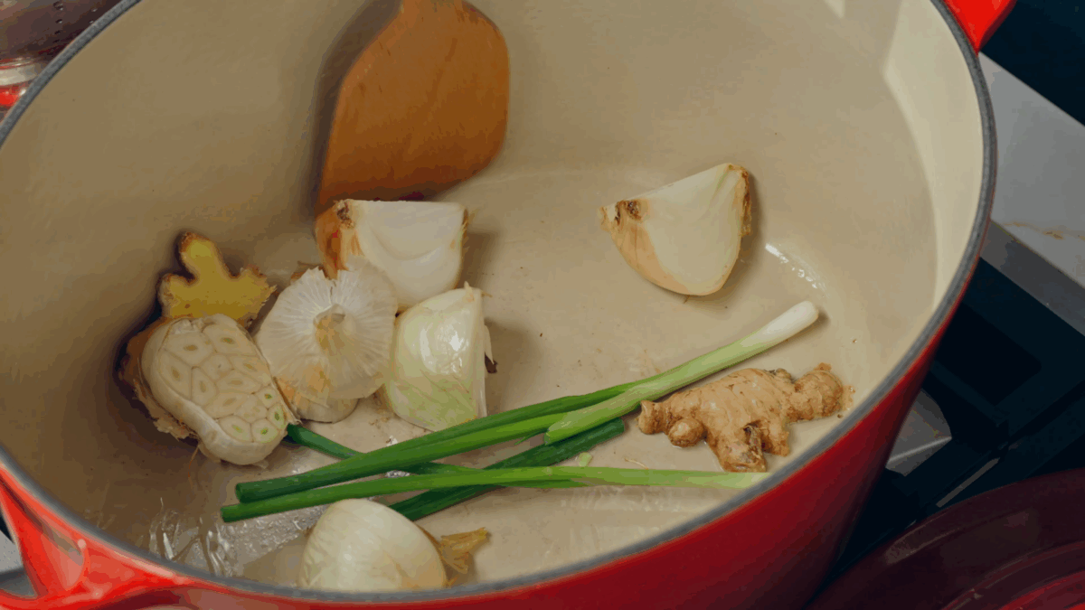 Onion, garlic, ginger, and scallions in a pot. 