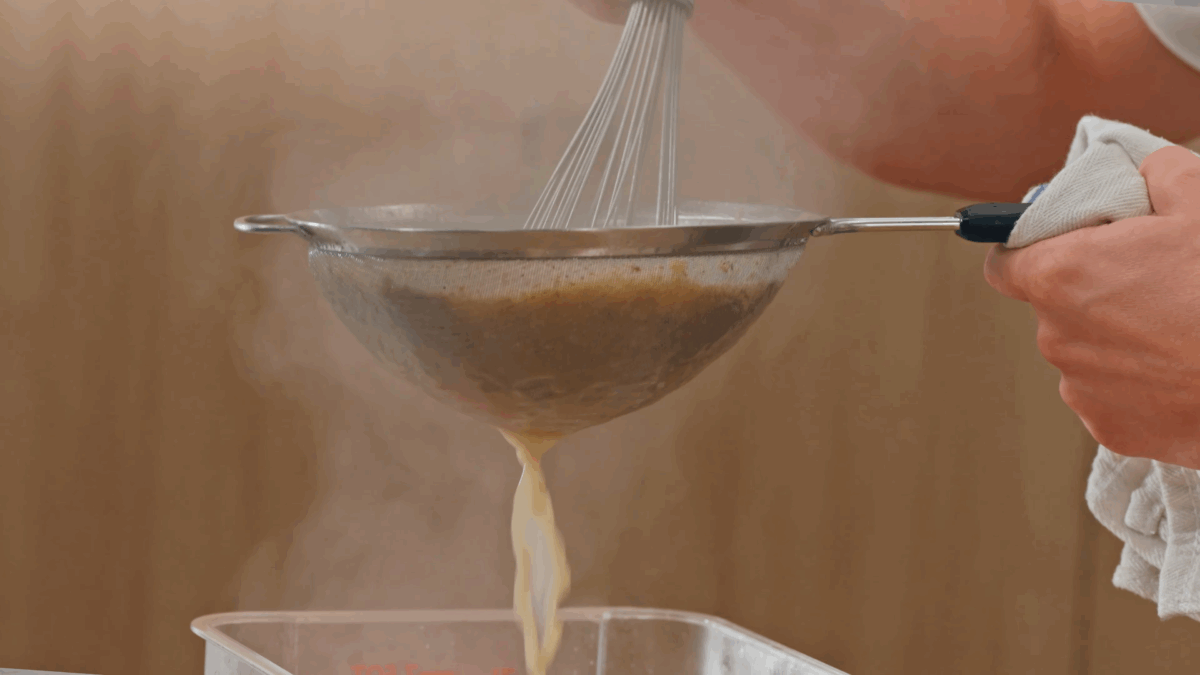 Nick DiGiovanni straining pork broth through a fine mesh sieve. 