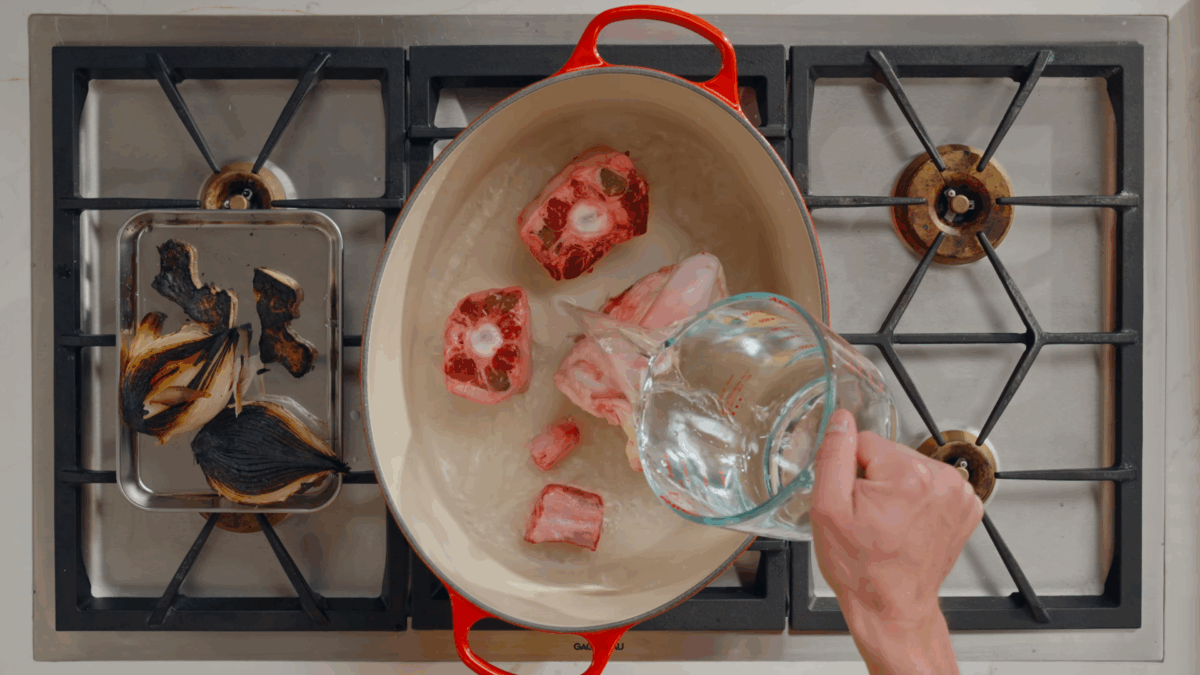 Nick DiGiovanni pouring water over bones in a pot on the stovetop.