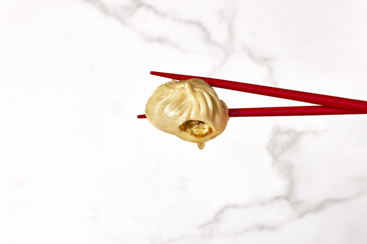 Two chopsticks holding a pork soup dumpling.