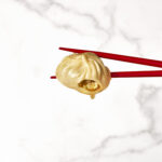 Two chopsticks holding a pork soup dumpling.