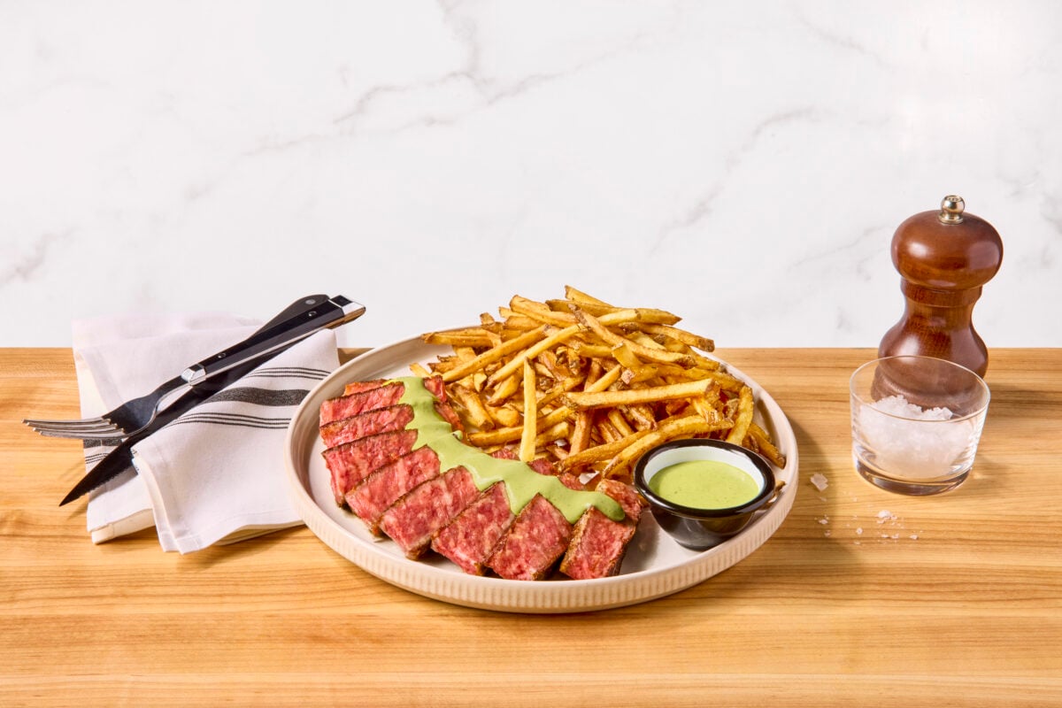 A plate of steak frites with a creamy green herb sauce.