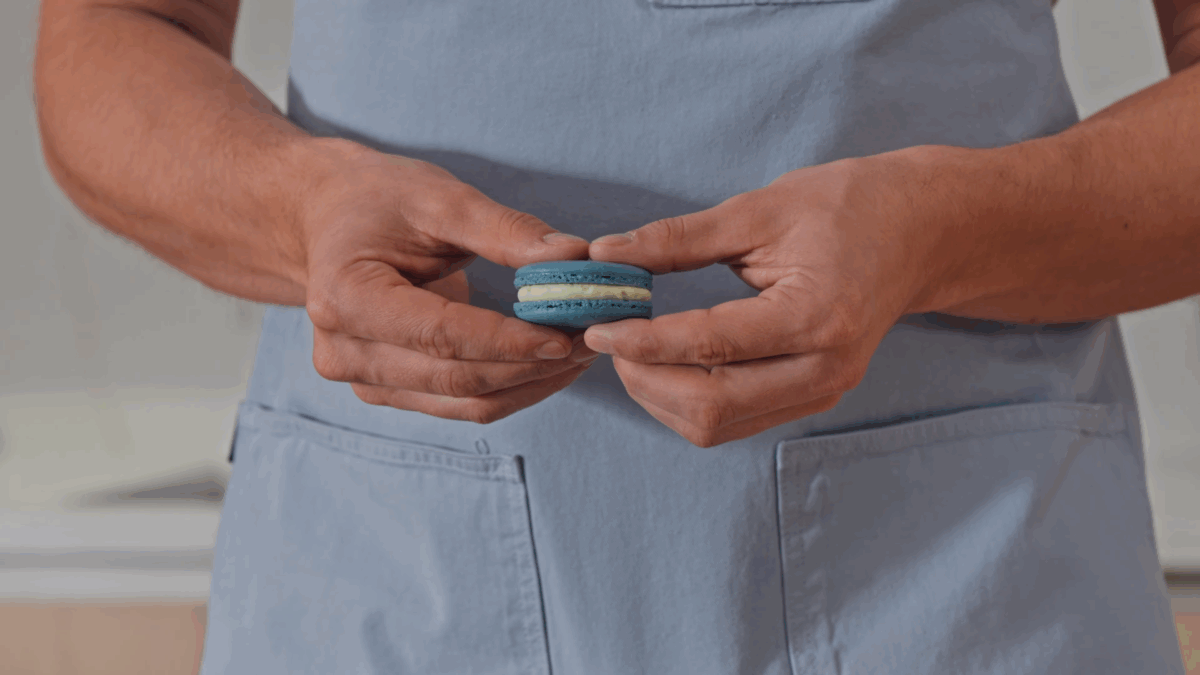 Nick DiGiovanni holding a blueberry macaron. 