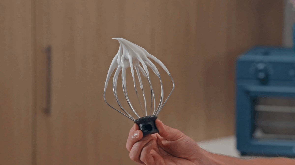 Nick DiGiovanni holding a whisk attachment coated in meringue. 