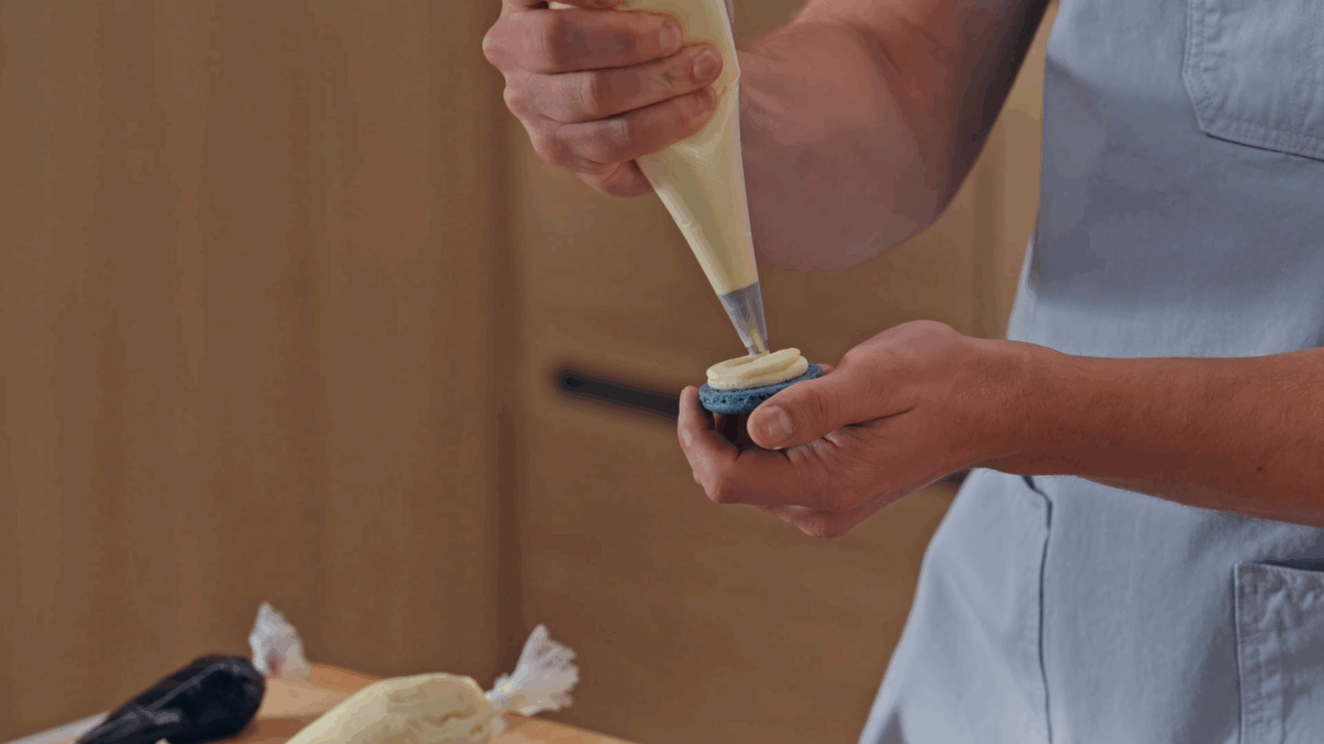 Nick DiGiovanni piping buttercream onto macaron shells. 