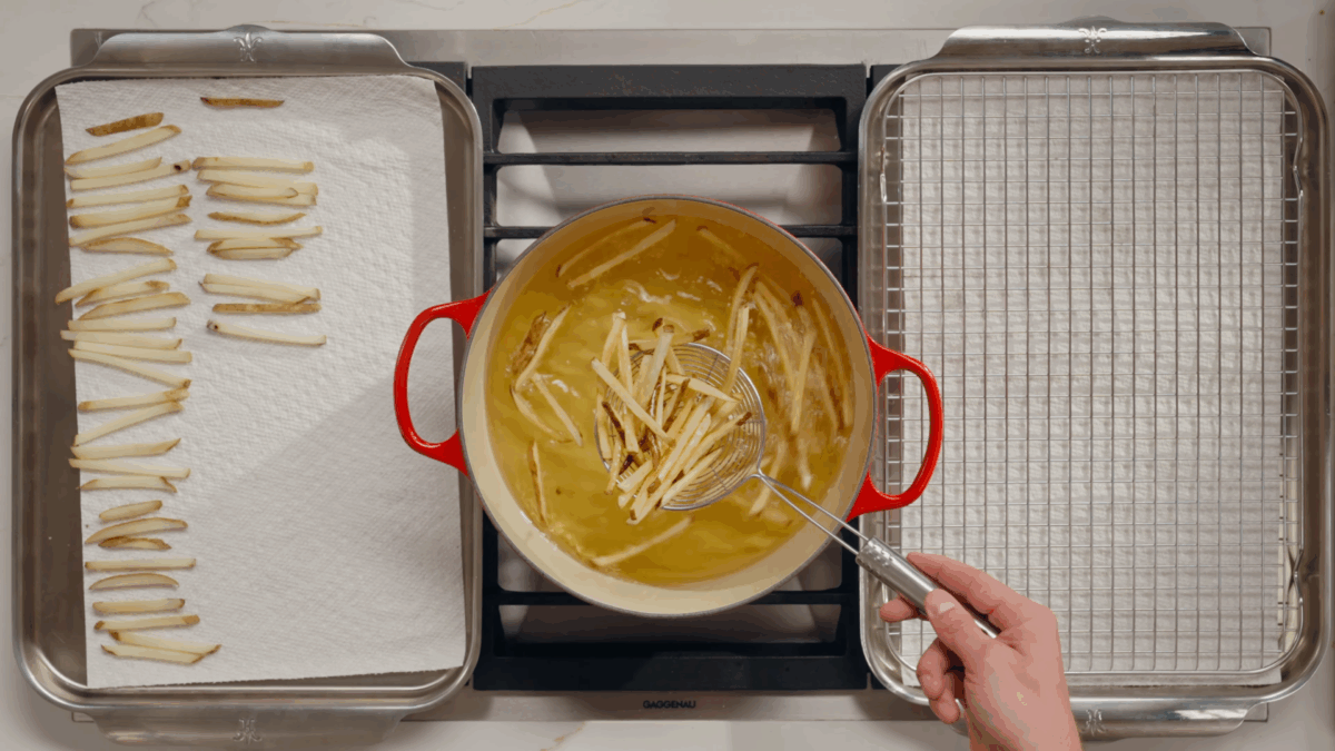 Nick DiGiovanni lifting fried potatoes from a pot of oil.