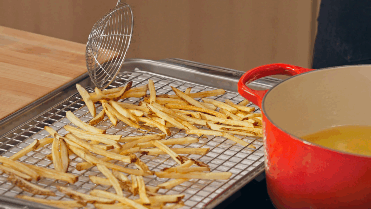 Nick DiGiovanni transferring French fries to a wire rack.