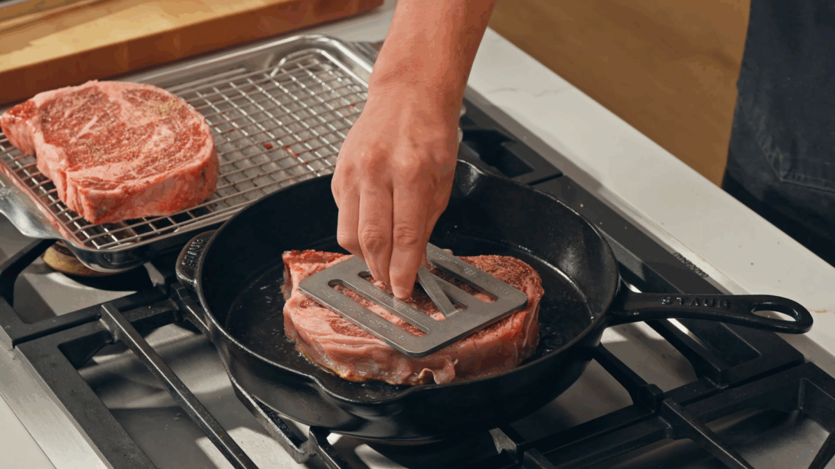 Nick DiGiovanni searing steak in a cast-iron skillet.