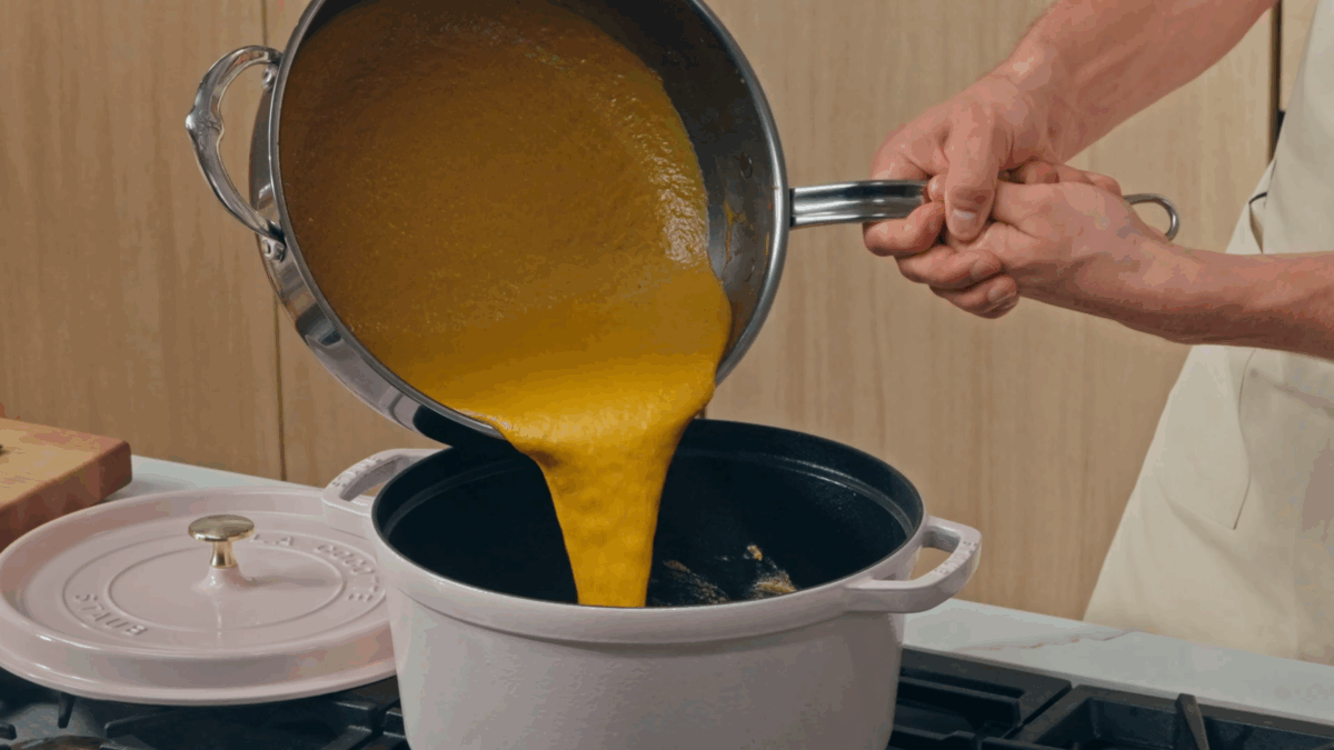 Nick DiGiovanni pouring katsu curry into a pot of roux.