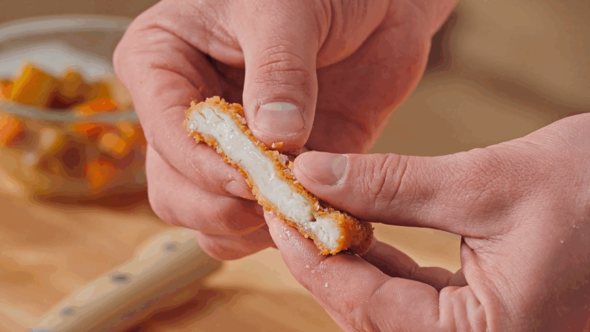 Nick DiGiovanni holding a slice of breaded, cooked katsu chicken.
